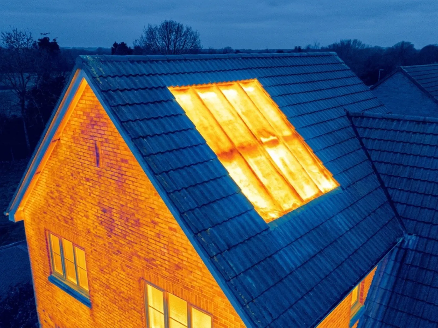 Thermal image of a roof slope showing a sharply defined warm rectangle where loft insulation is missing, against a cooler field where it is intact